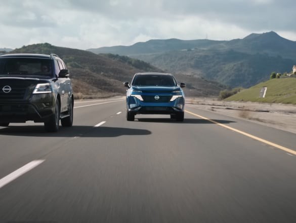 2026 Nissan Murano driving on rural road next to an SUV with hills in background
